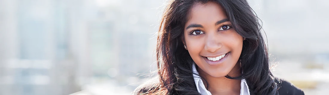 Dentist Canoga Park CA Dental Services A smiling person with dark hair and warm-toned skin looks directly at the camera while wearing a light shirt and a jacket.