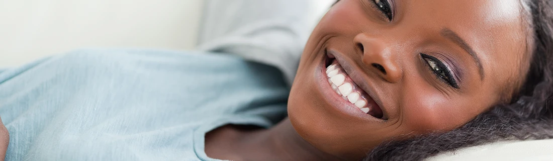 Dentist Canoga Park CA Scaling Root Planing A woman lies down, smiling warmly at the camera, with radiant skin and expressive eyes.